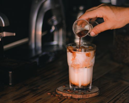 Iced macchiato met cold brew die over ijs en havermelk wordt geschonken