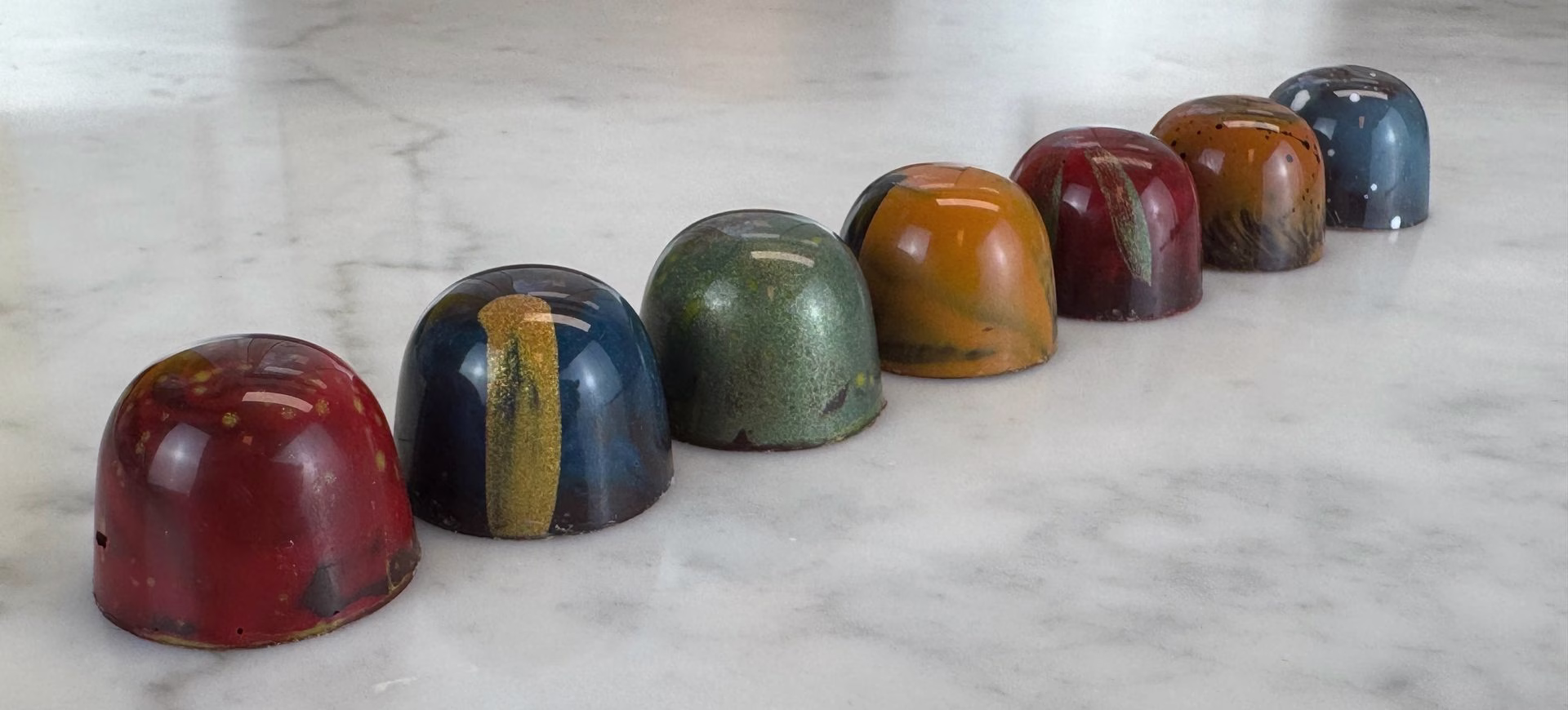Een rij handgemaakte bonbons van Dave's Koffiebranderij op marmer